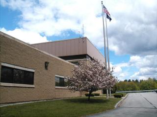 Water Utilities Building taken from the left side - showing flagpole and small ornamental tree in front. The tree is in bloom
