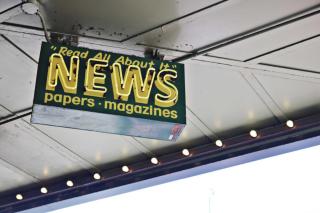 A neon sign that reads " read all about it, news, papers, magazines"